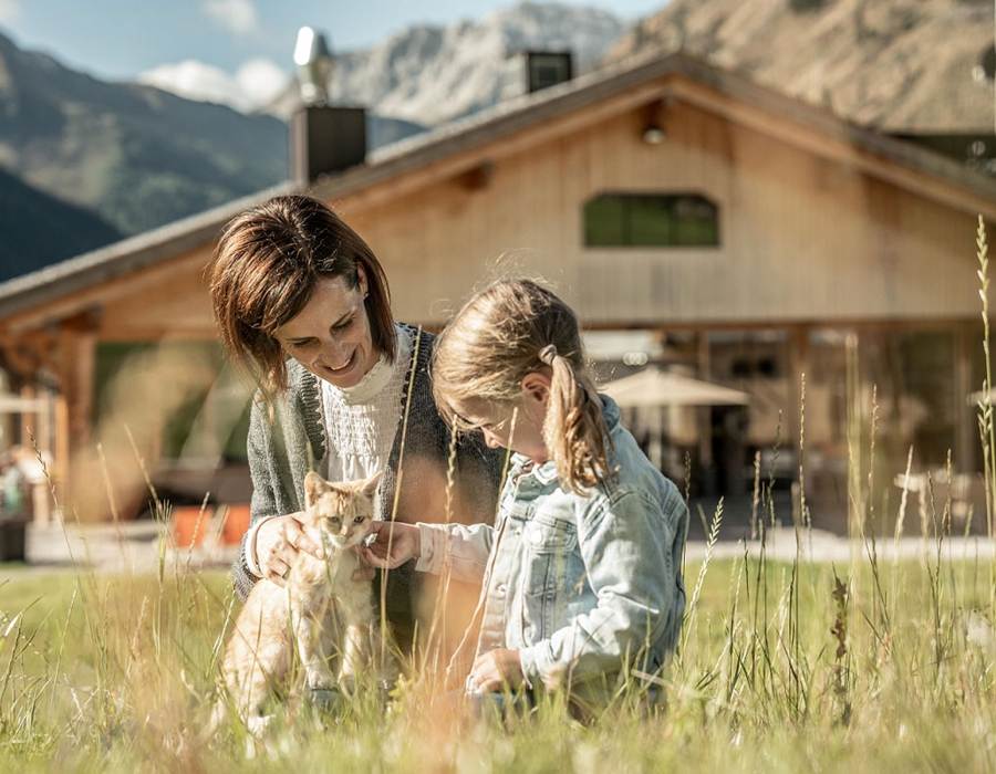 Mutter mit Tochter beim Katze streicheln im Urlaub